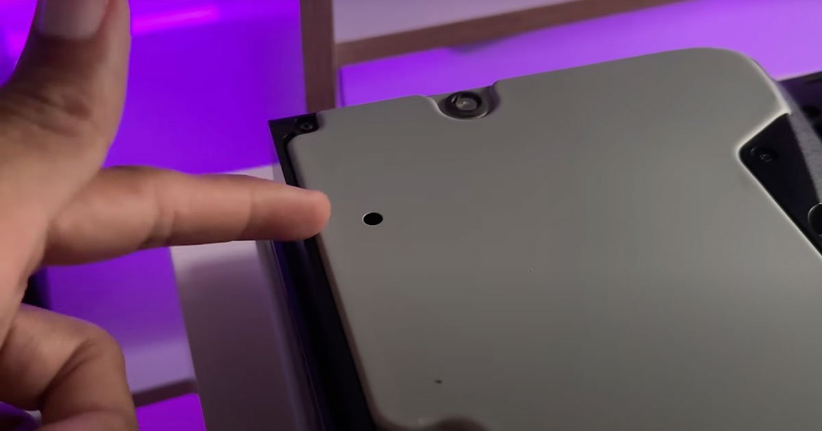 Mano señalando el tornillo oculto dentro de la PS5 Slim