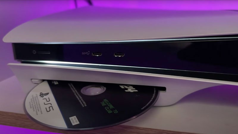 Consola PS5 expulsando un disco de videojuego desde el lector.